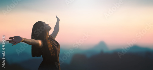Celebration of life day concept: Happy Asian girl raised hand on blurred mountain sunrise background. Phang-nga, Thailand, Asia photo