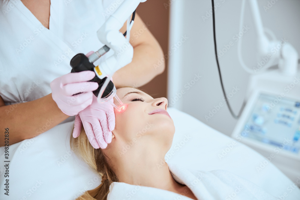 Naklejka premium Young woman undergoing a non-invasive cosmetic procedure