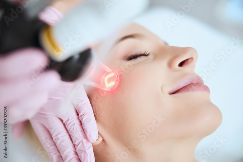 Calm pleased lady undergoing a cosmetic procedure photo