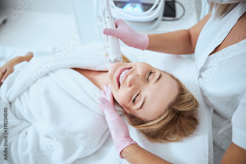 Young female client enjoying the microneedling procedure photo