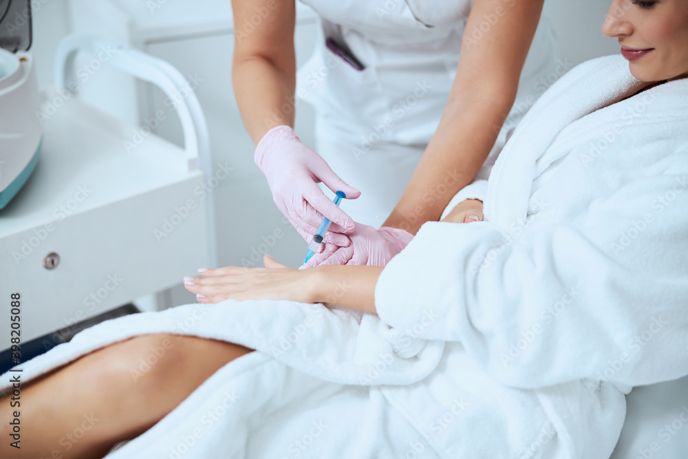 Woman client undergoing the hand rejuvenation procedure Woman client undergoing the hand rejuvenation procedure
