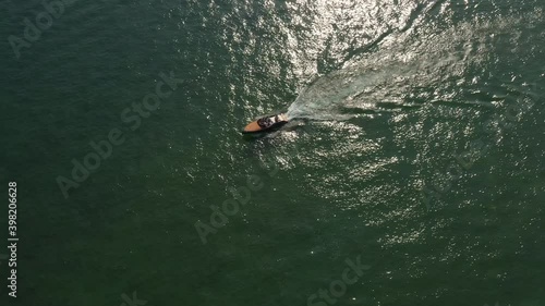 Top view of a wooden boat sailing to the blue sea. Wooden runabout in the rays of the sun on turquoise water. Drone view of a boat  the blue clear waters. Classic Italian motorboat.