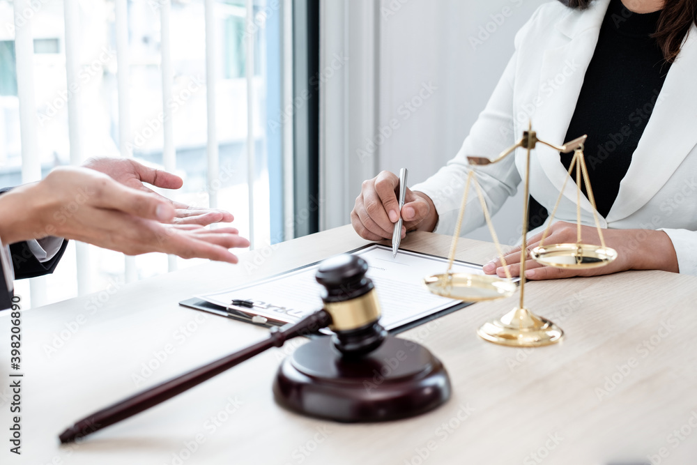 A male lawyer or a judge counseling clients about judicial justice and prosecution with scales, judges gavel, legal documents legal services concept A male lawyer or a judge counseling clients about judicial justice and prosecution with scales, judges gavel, legal documents legal services concept