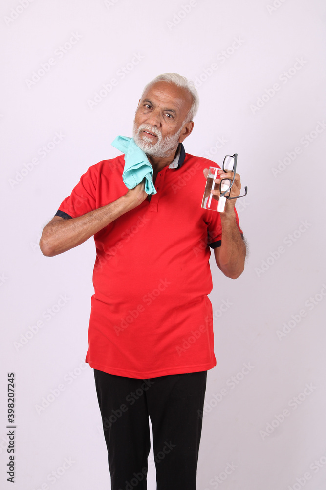 senior indian man holding glass of water while or after weight training or gym, keeping himself dehydrated senior indian man holding glass of water while or after weight training or gym, keeping himself dehydrated