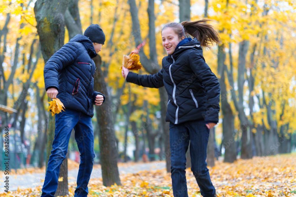 teen girl and boy running through the park and enjoys autumn, beautiful nature with yellow leaves teen girl and boy running through the park and enjoys autumn, beautiful nature with yellow leaves