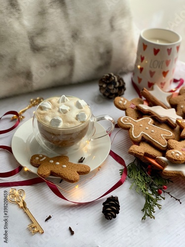 Winter cappuccino coffee in a white cup with man christmas gingerbread cookies. Christmas mood. New Year atmosphere. Cozy home.