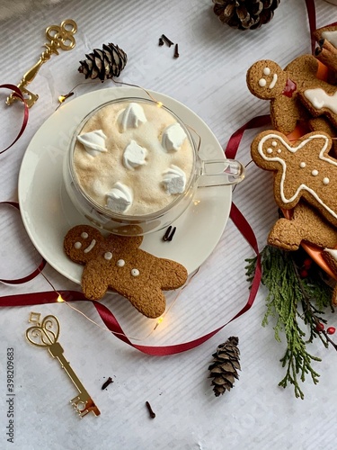 Hot winter drink: chocolate with whipped cream in glass mug. Christmas time. Cozy home atmosphere, white background. Homemade gingerbread cookies, christmas lights. Banner, copy space for text