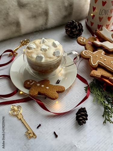 Hot winter drink: chocolate with whipped cream in glass mug. Christmas time. Cozy home atmosphere, white background. Homemade gingerbread cookies, christmas lights. Banner, copy space for text