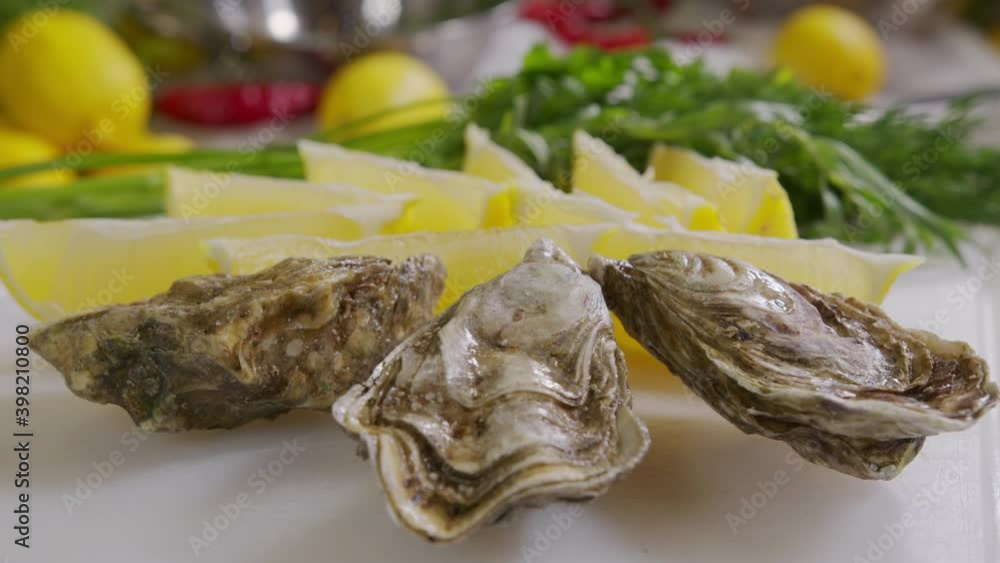 Oysters with lemon closeup. Fresh Oyster on half shell on big plate in restaurant. Served table. 4K UHD video slow motion. Oysters with lemon closeup. Fresh Oyster on half shell on big plate in restaurant. Served table. 4K UHD video slow motion.