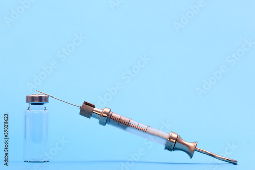 antique syringe made of metal and glass and phial on blue background. free space for text. copyspace