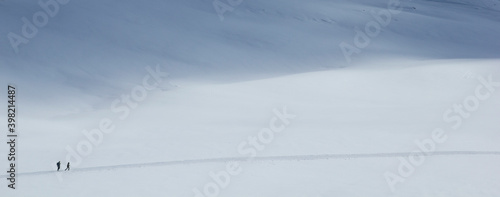 two people in the snow with a long way to go in a very lonely landscape