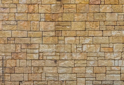 Pattern and texture of rectangular yellow dry stone block wall. It was constructed from stones without any mortar to bind them together. photo