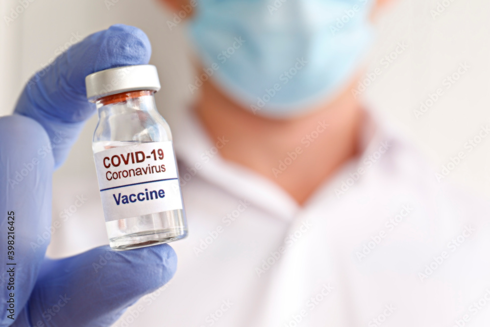 Macro shot of a doctor wearing face mask and latex gloves demonstrating the new covid-19 vaccine in vial. Close up portrait, copy space, background. Macro shot of a doctor wearing face mask and latex gloves demonstrating the new covid-19 vaccine in vial. Close up portrait, copy space, background.