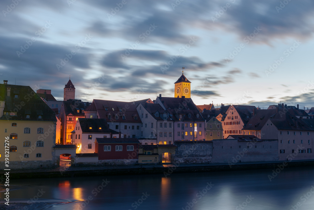 Panoramic view of the famous skyline of Regensburg in Bavaria seen from the Stone Bridge with dramatic clouds in evening sky
