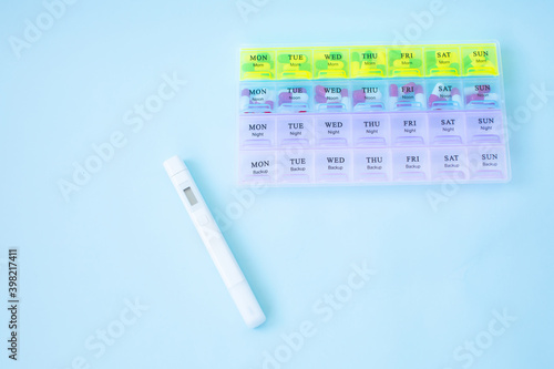 Plastic container with pills on blue background.