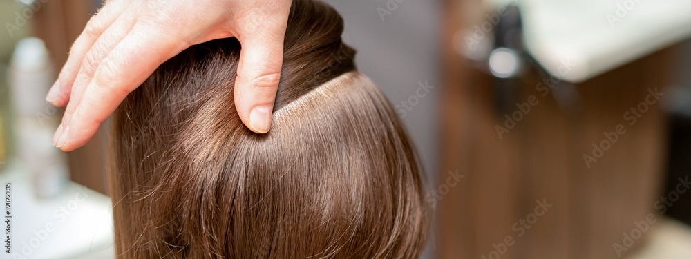 Fototapeta premium Hairdresser checks short brown hairstyle of a young woman in a beauty salon