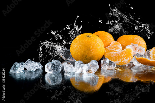 Fototapeta Naklejka Na Ścianę i Meble -  tangerines on a black background, water splash, crushed ice, ice cubes