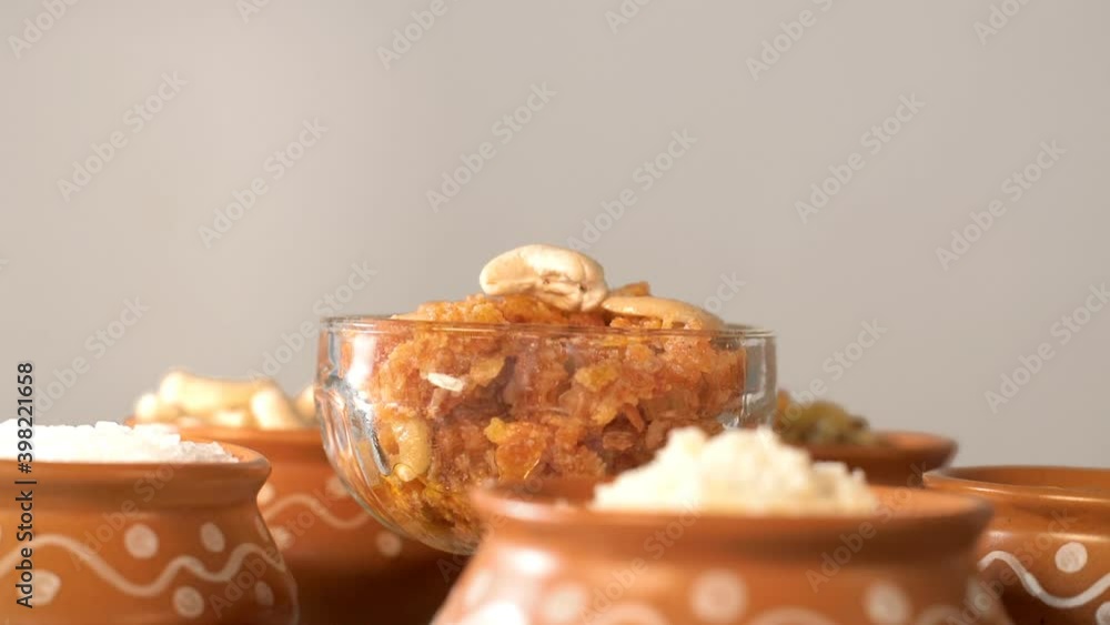 A beautiful decorative bowl of Gajar Ka Halwa/carrot pudding kept with its ingredients. Popular Indian sweet dish Gajar Ka Halwa prepared with grated carrot  Khoa  milk  sugar  Desi ghee  and dry f...