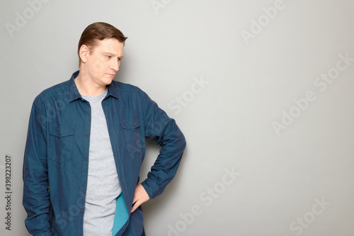 Portrait of serious concentrated man holding hand on hip and thinking