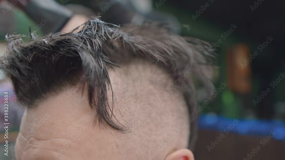 Hairdresser dries hair on the client's head with a hairdryer Hairdresser dries hair on the client's head with a hairdryer