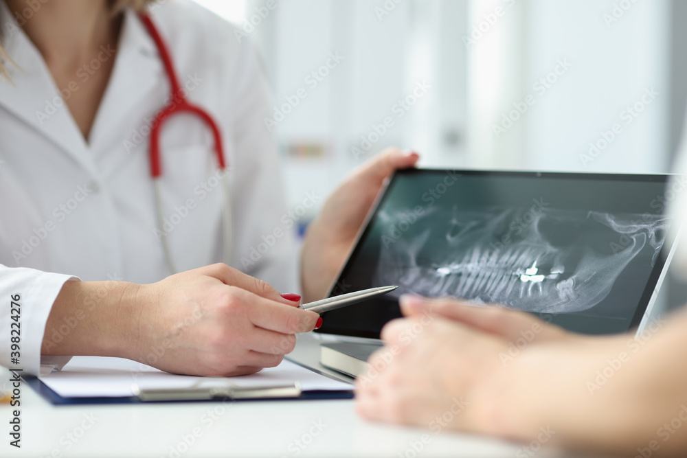 Fototapeta premium Dentist showing patient tablet with x-ray of teeth in clinic closeup