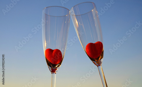 Couple glasses of champagne with red marmalade hearts on blue sky background, selective focus photo