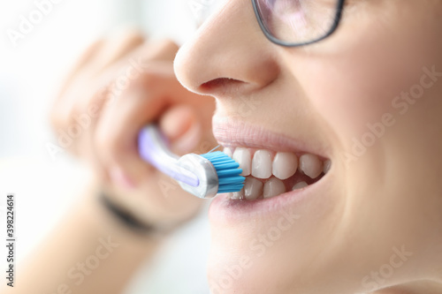 Woman brushing her teeth with brush in bathroom closeup