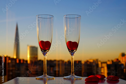 Couple glasses of champagne and red marmalade hearts on city view and blue sky background in Saint-Petersburg, Russia, Lahta center building. Copy space, selective focus © Olga Kazanovskaia 