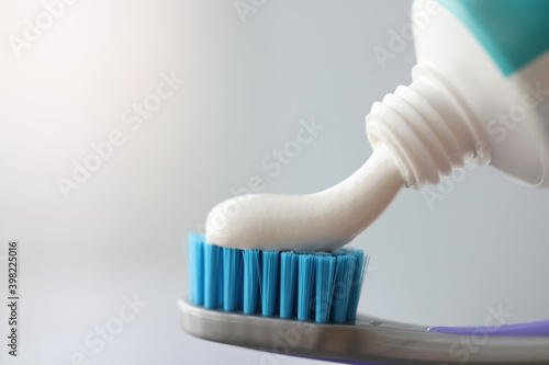 Toothpaste flowing out of white tube onto toothbrush closeup