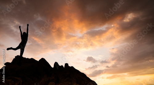Silhouette of woman celebrating success standing on top mountain at sunrise  Concept for success.