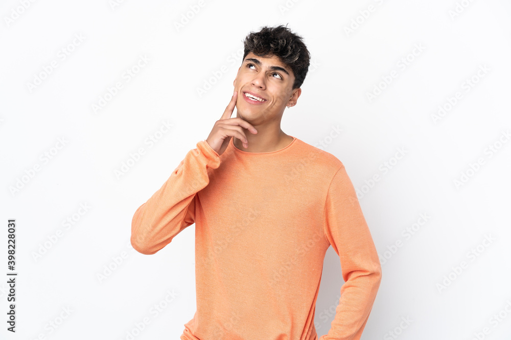 Fototapeta premium Young man over isolated white background thinking an idea while looking up