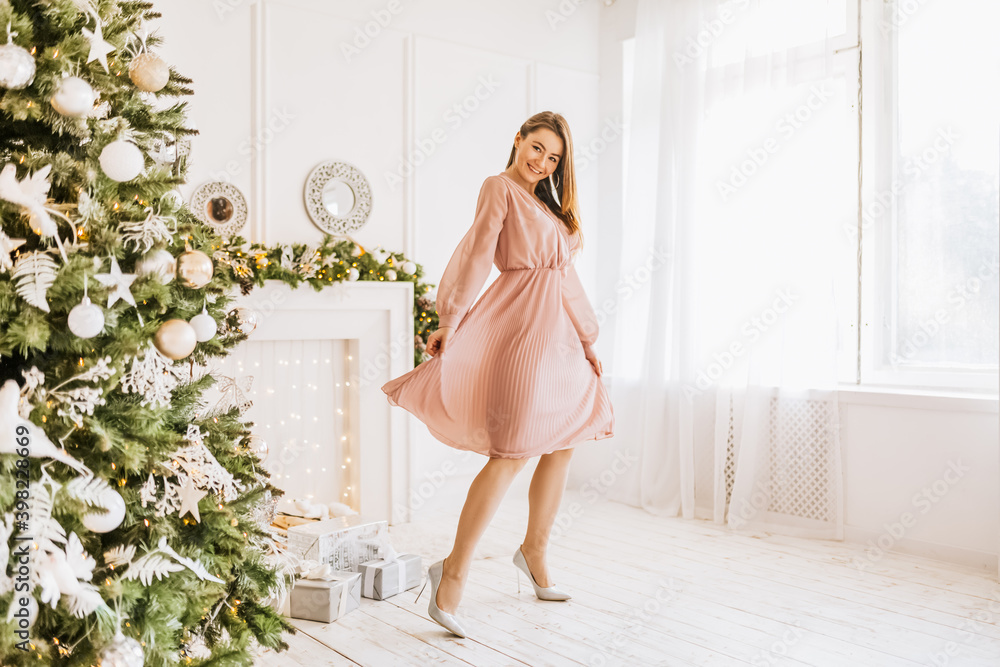 Beautiful cheerful happy young girl with christmas gifts on the background of a new year tree at home Beautiful cheerful happy young girl with christmas gifts on the background of a new year tree at home