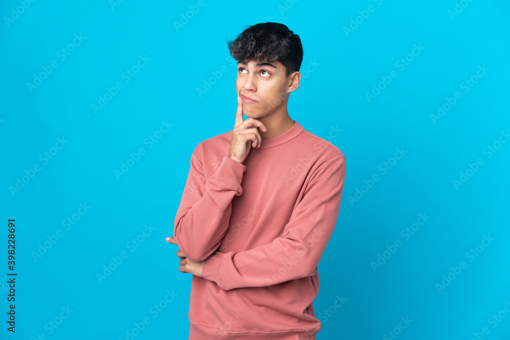 Fototapeta premium Young man over isolated blue background having doubts and thinking