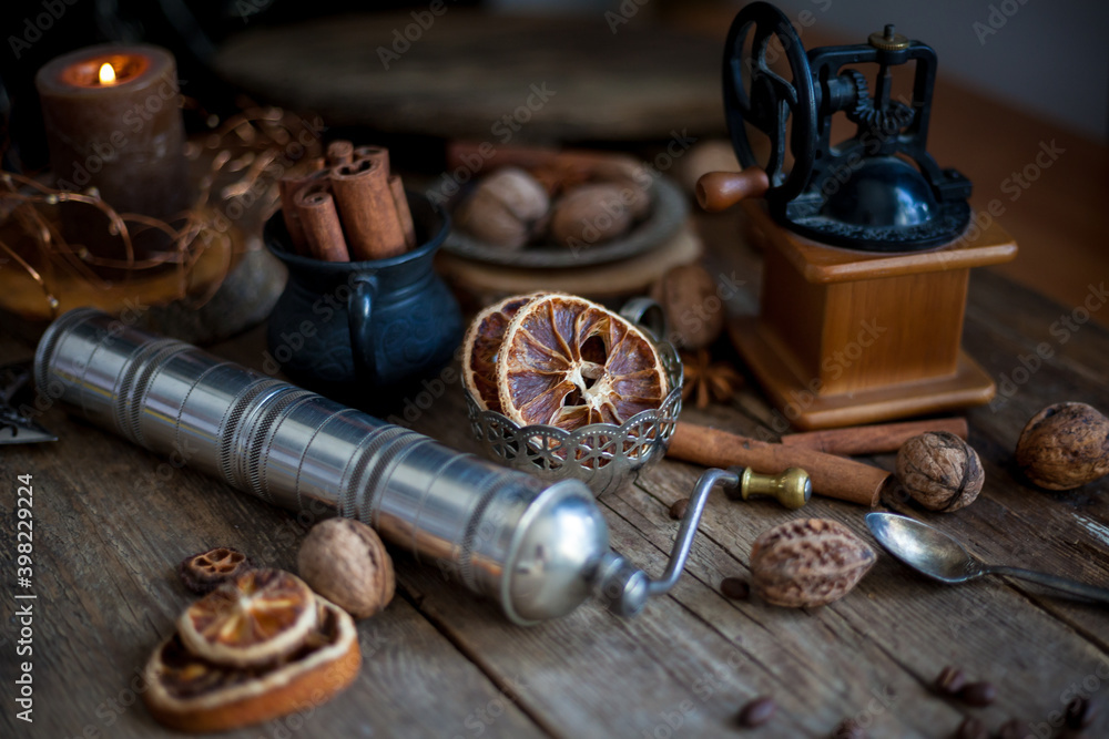 Cinnamon sticks, dried orange, star anise, aromatic spices on a wooden table. Christmas lights garlands. New Year's still life. Manual coffee grinder and beans. Food on the table.