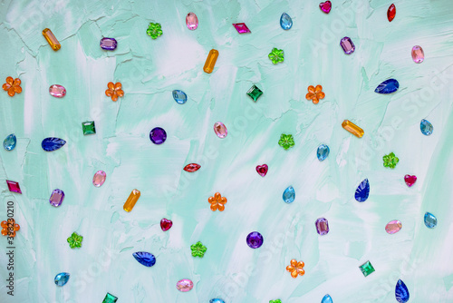 фотографія Trendy plastic colorful crystal rhinestone for sewing on green abstract background
