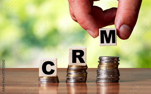 CRM word symbol - business concept. Hands put wooden block on stacked increasing