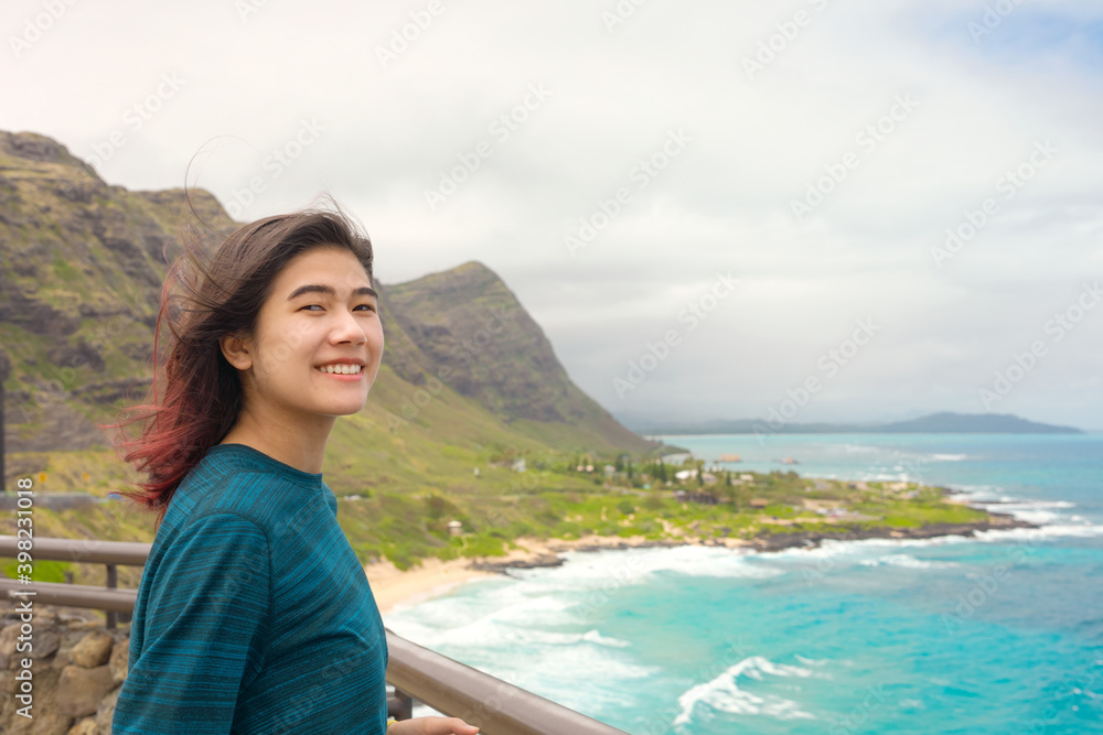 Teen girl standing above tropical Hawaiian ocean scenery