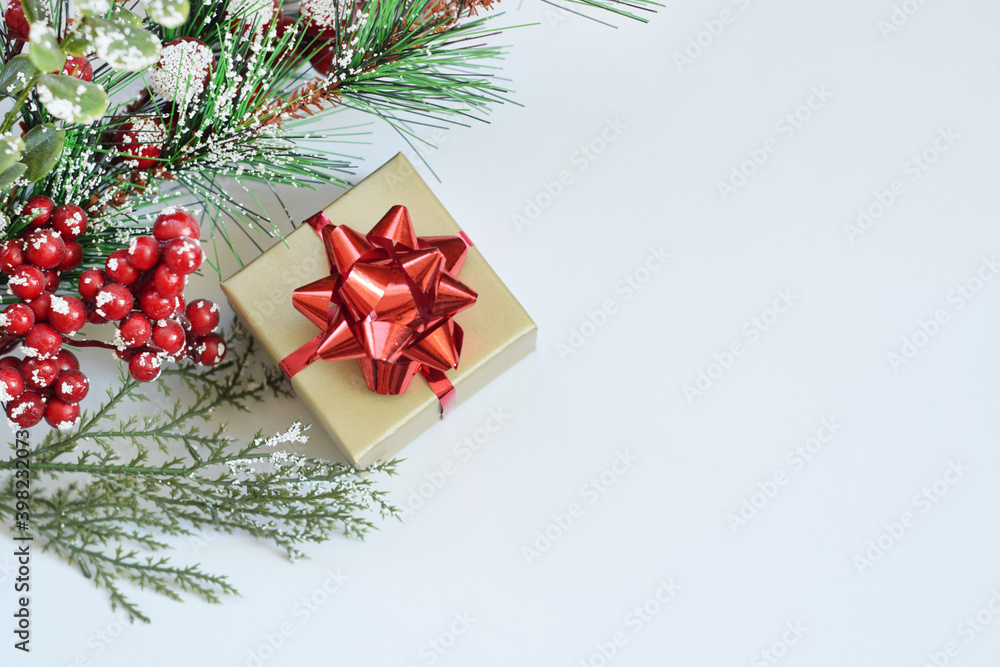 Christmas golden gift box with a red bow and coniferous branches with red berries on a white background. Christmas golden gift box with a red bow and coniferous branches with red berries on a white background.