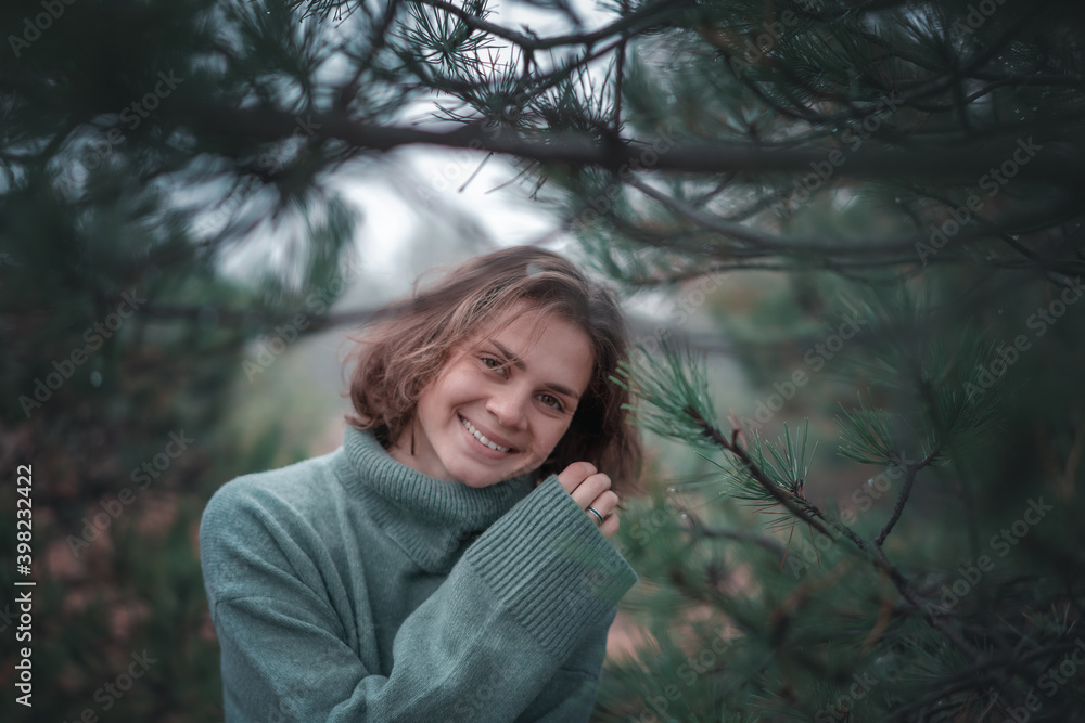 Young beautiful happy woman walking in fir forest enjoying nature meditating outdoors