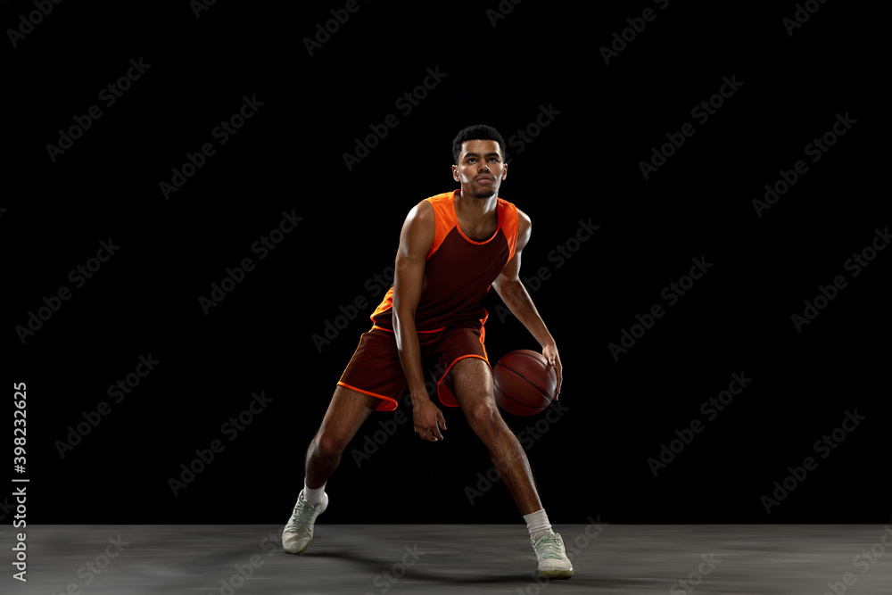 Leader. Young purposeful african-amrican basketball player training, practicing in action, motion isolated on black background. Concept of sport, movement, energy and dynamic, healthy lifestyle.
