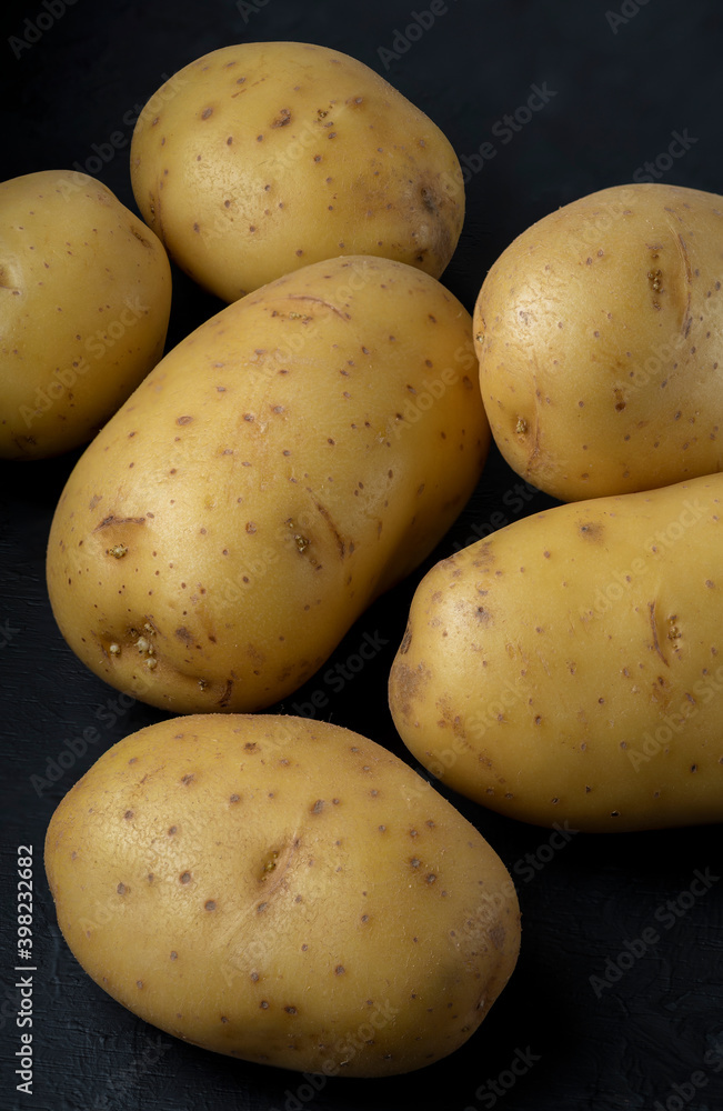 Many potatoes on a black background Stacked image Dark food photography Many potatoes on a black background Stacked image Dark food photography