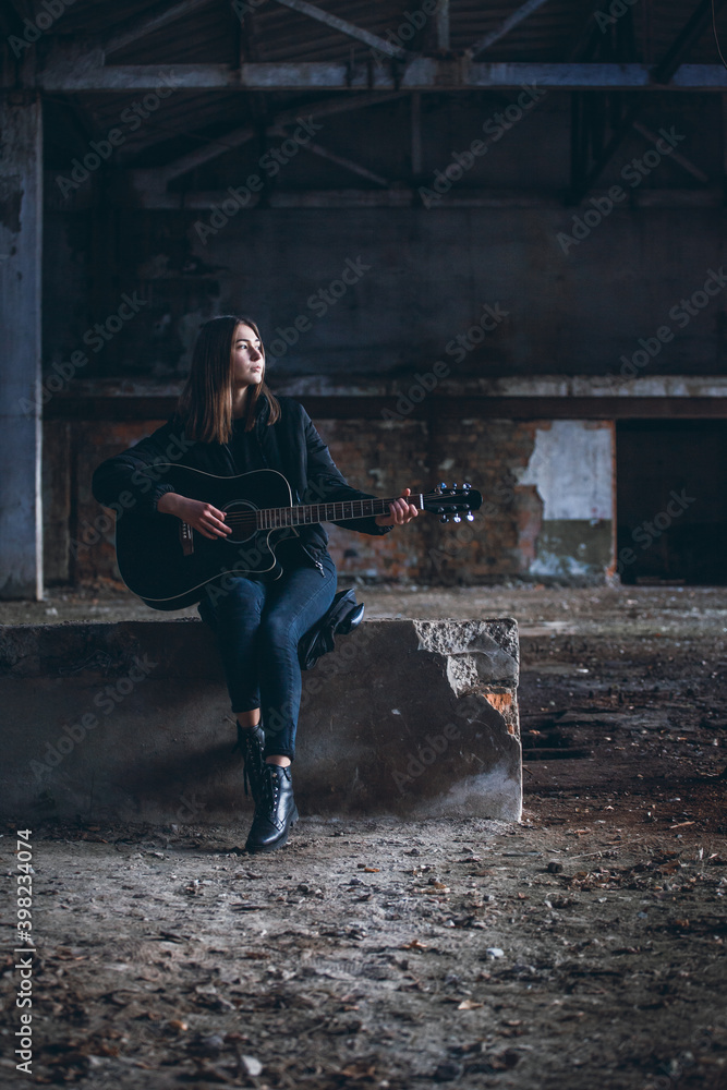 Young Beautiful Girl with Guitar in Dark Empty Factory Hall
