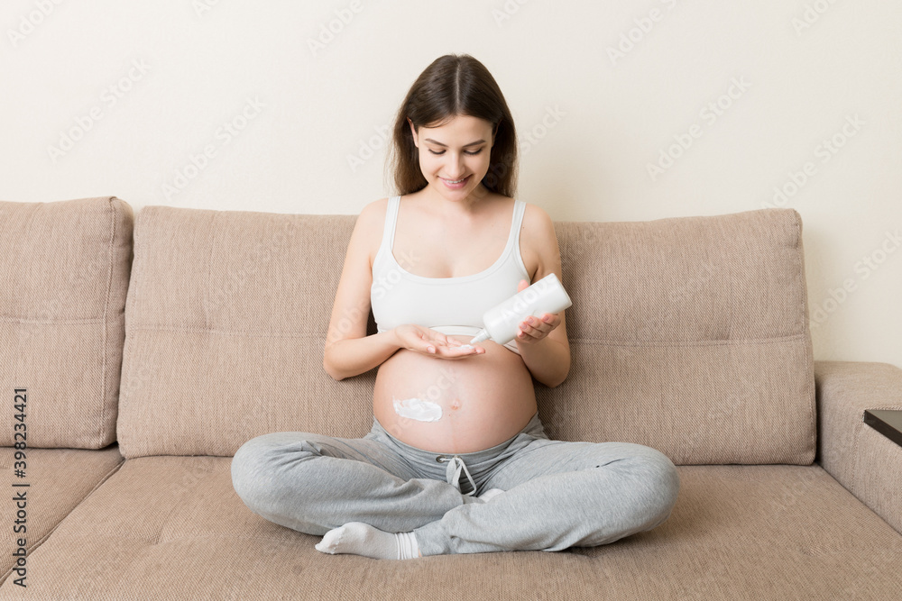 pregnant woman applying stretch mark cream to belly. pregnancy, people and maternity concept. pregnant apply anti-stretch mark cream on her belly pregnant woman applying stretch mark cream to belly. pregnancy, people and maternity concept. pregnant apply anti-stretch mark cream on her belly