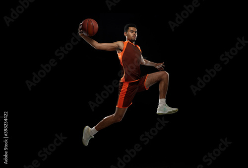 Upgrade. Young purposeful african-amrican basketball player training, practicing in action, motion isolated on black background. Concept of sport, movement, energy and dynamic, healthy lifestyle. © master1305