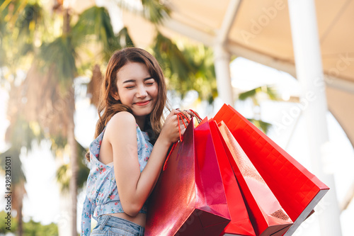 Happy young adult asian woman with shopping bags.