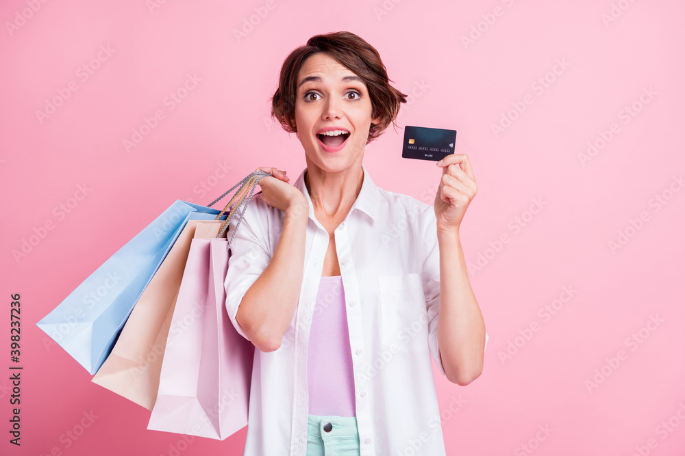 Photo of funny amazed young lady wear white shirt holding bank card colorful bargains isolated pink color background Photo of funny amazed young lady wear white shirt holding bank card colorful bargains isolated pink color background