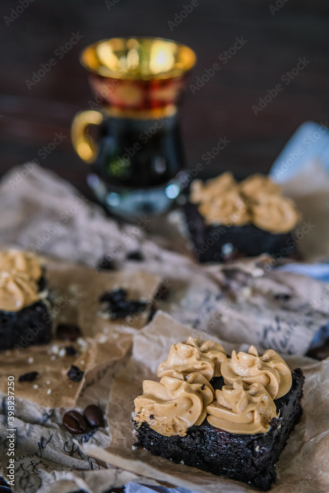 Fototapeta premium Cup of coffee with chocolate brownies with cream and coffee beans on rustic recipe papers