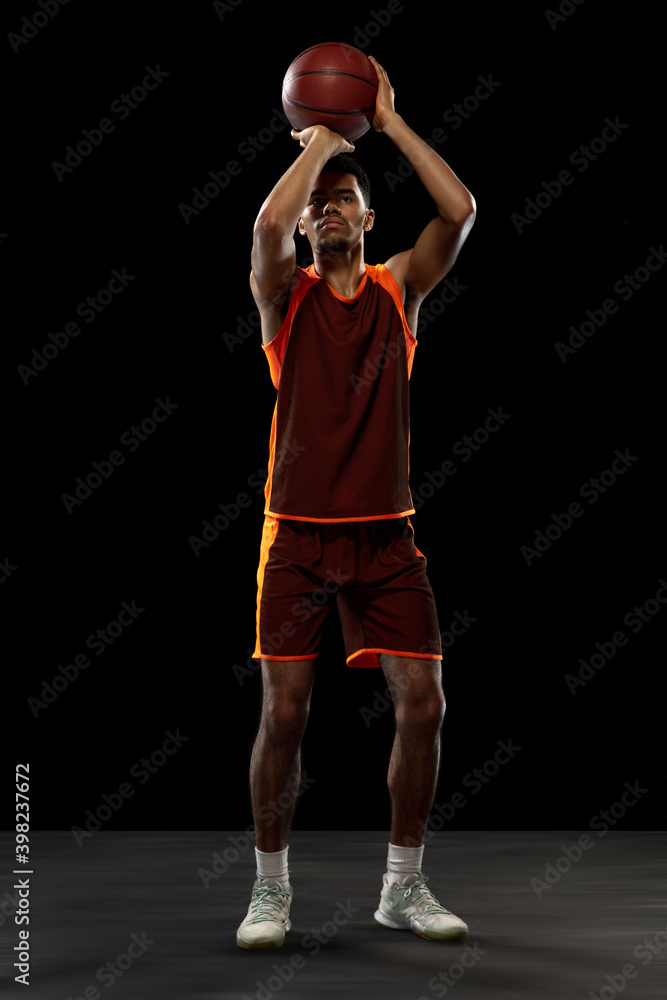 Champion. Young purposeful african-amrican basketball player training, practicing in action, motion isolated on black background. Concept of sport, movement, energy and dynamic, healthy lifestyle.