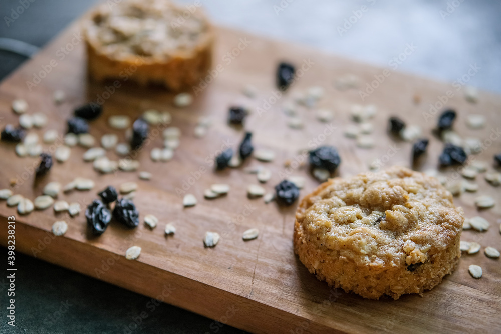 Oatmeal cookies with raisins on rustic wooden chopping board background Oatmeal cookies with raisins on rustic wooden chopping board background