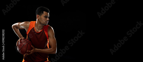 Speed. Young purposeful african-amrican basketball player training, practicing in action, motion isolated on black background. Concept of sport, movement, energy and dynamic, healthy lifestyle.